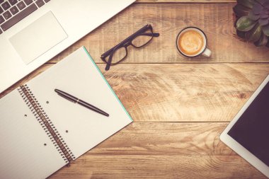 Dizüstü bilgisayar, dizüstü bilgisayar, kalem, gözlük, kahve fincanı ve tablet bilgisayar ile Rustik ahşap masa. Kopyalama alanı ile modern çalışma alanı. Filtre tonlama efekti.