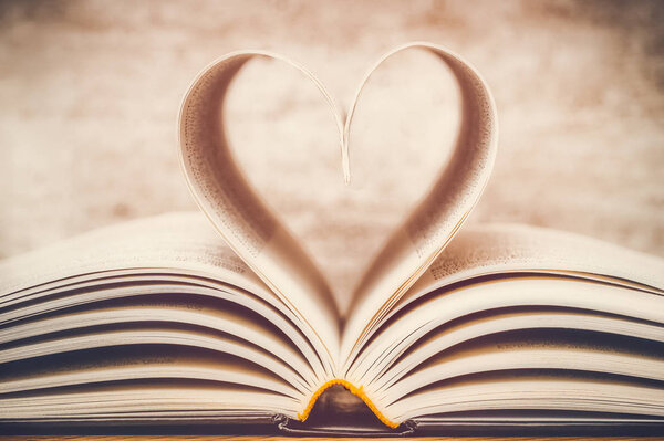 Heart shape made with book pages closeup. Toned and dreamy image