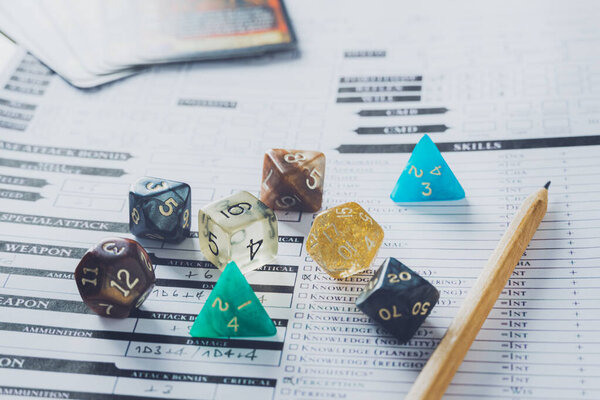 Colorful dices and pencil on a character sheet. Role playing game or rpg concept.