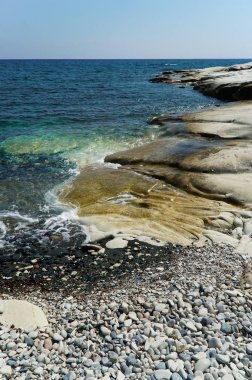Deniz kıyısında turkuaz su ve kayalıkları olan bir sahil.