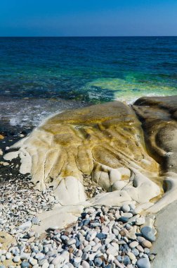 Deniz kıyısında turkuaz su ve kayalıkları olan bir sahil.