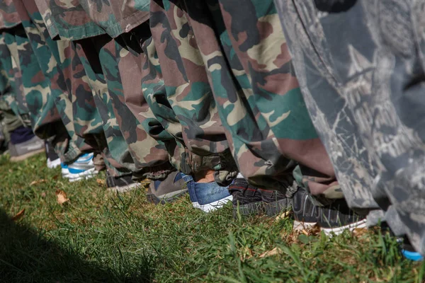 Military training non-professionals. Legs of people in uniform and civilian shoes.