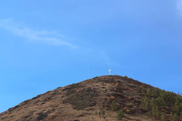 Pravoslavný kříž na vrcholku hory proti čisté obloze — Stock fotografie
