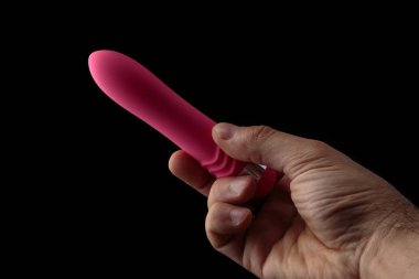 Sanatsal ışık ile siyah arka plan üzerinde erkek elinde Pembe vibratör