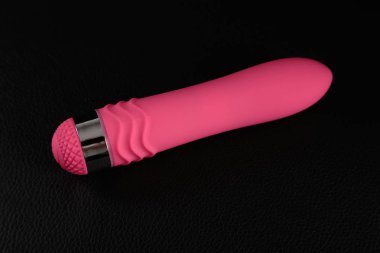 Siyah deride pembe yapay penis. Karanlık arka plan. Sanatsal aydınlatma.