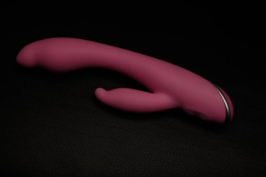 Siyah deride pembe yapay penis. Karanlık arka plan. Sanatsal aydınlatma.