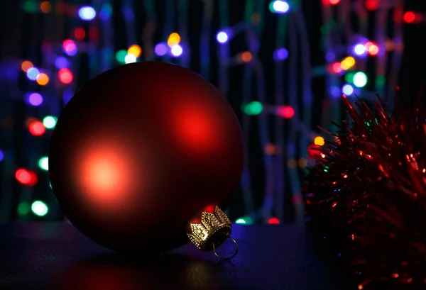 Boule de Noël rouge à l'obscurité. Hors foyer Noël lumières arrière-plan . — Photo