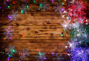 Ahşap arka planda Noel ışıkları ve kar taneleri