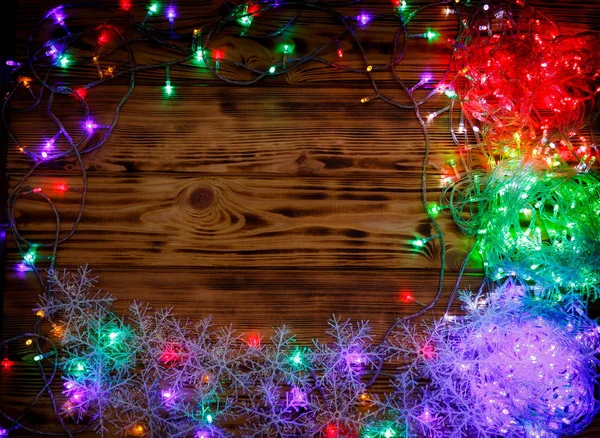 Luces de Navidad y copos de nieve sobre fondo de madera — Foto de Stock