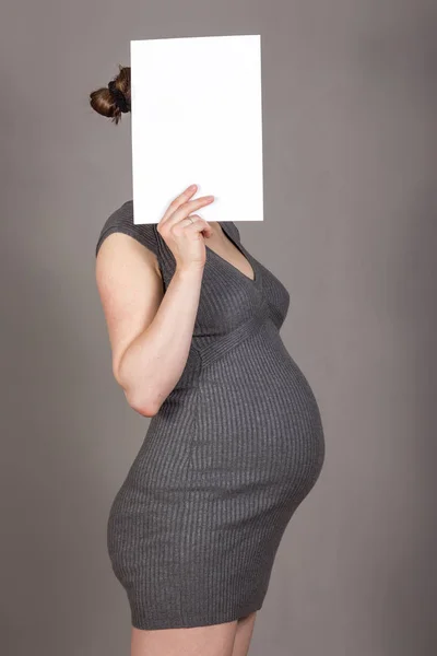 Femme enceinte sur fond gris neutre avec un morceau de papier. lieu d'inscription . — Photo