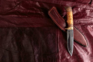 Kırmızı deri arka plan üzerinde avcılık bıçağı
