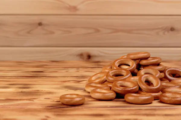 Heap of bagels scattered on the wooden table with copy space — Stock Photo, Image