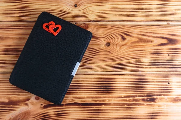 Libro electrónico con dos corazones en el estuche sobre fondo de madera. Concepto de libro romántico . — Foto de Stock