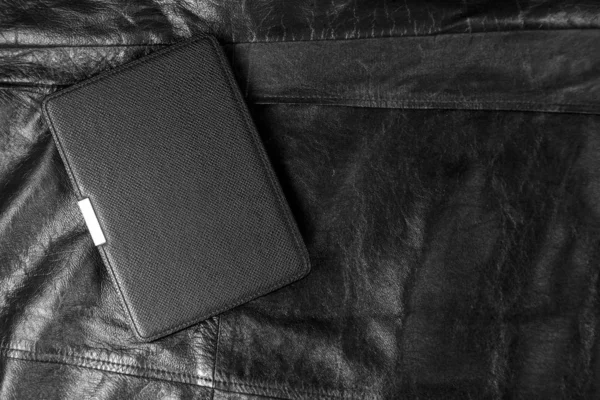 Electronic book in the case on black leather background