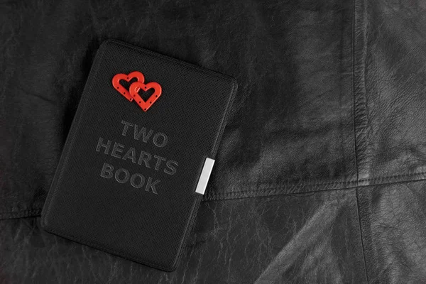 Electronic book in a case with the inscription with two hearts on leather background. Romantic book concept.