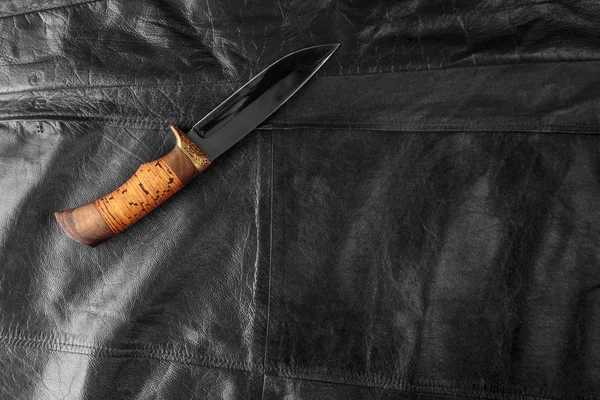 黒い革の背景に狩猟ナイフ — ストック写真
