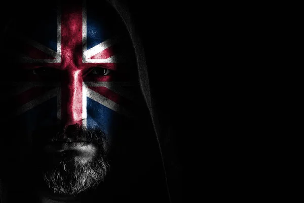 Gri sakallı, yüzünde Büyük Britanya bayrağı olan, siyah arka planda keskin gölgeleri olan bir kapüşonlu vahşi bir adam. Kopyalama alanı — Stok fotoğraf