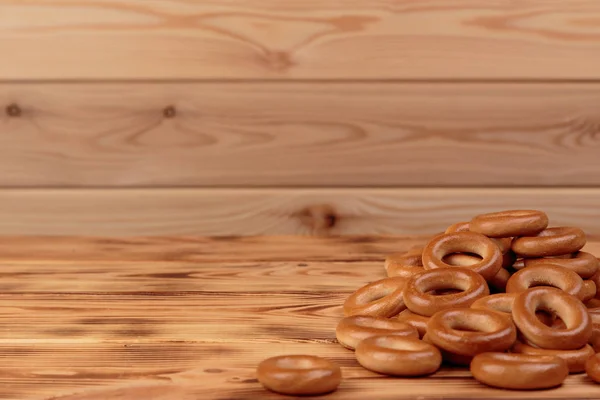 Heap of bagels scattered on the wooden table with copy space — Stock Photo, Image