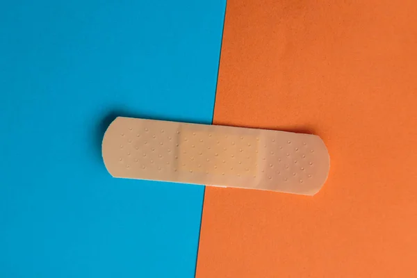 Adhesive bandage or Sticking plaster on a two colored paper background.