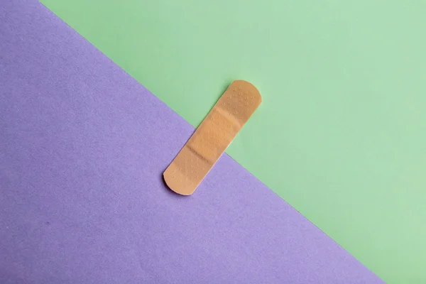 Adhesive bandage or Sticking plaster on a two colored paper background. — Stock Photo, Image