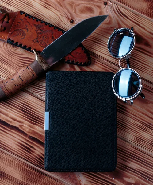 Libro electrónico en caso de cuchillo de caza y gafas de sol sobre fondo de madera. Concepto de libro de aventura o detective . — Foto de Stock