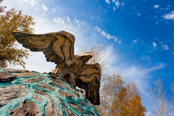 Скульптура парящего орла на фоне яркого неба
