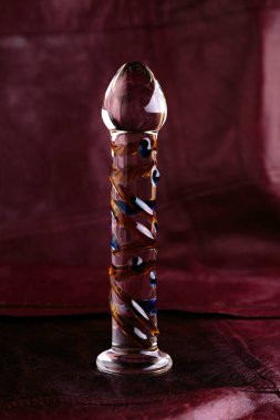 Glass dildo on a red leather background 
