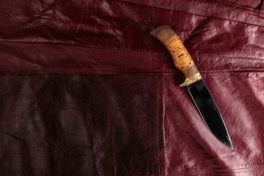 Kırmızı deri arka plan üzerinde avcılık bıçağı