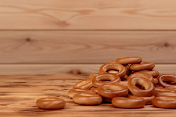 Heap of bagels scattered on the wooden table with copy space — Stock Photo, Image