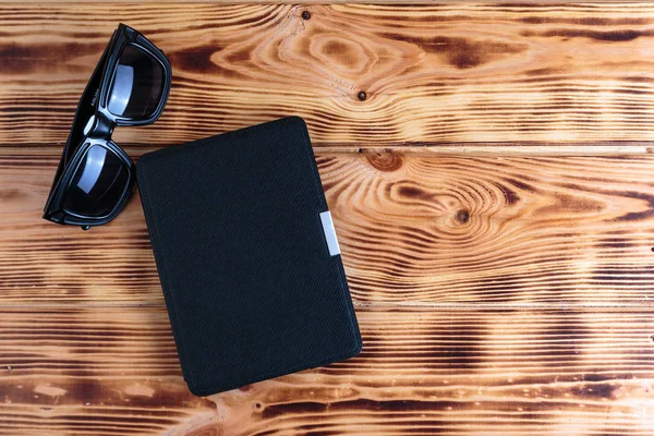 Libro electrónico en caso de gafas de sol sobre fondo de madera. Concepto de libro de aventura o detective . —  Fotos de Stock