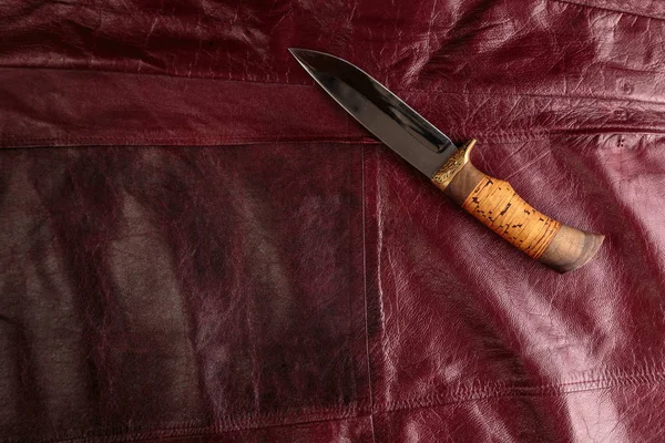 Kırmızı deri arka plan üzerinde avcılık bıçağı — Stok fotoğraf