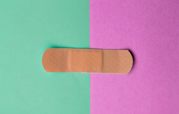 Ligadura adesiva ou adesivo gesso em um fundo de papel de duas cores . — Fotografia de Stock