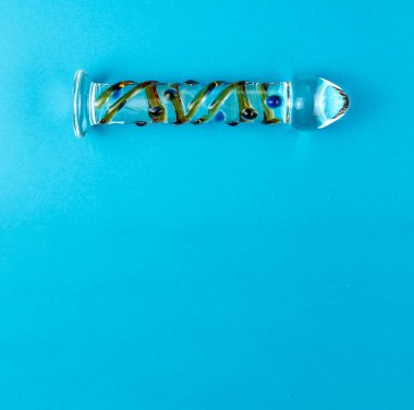 Kopya alanı ile düz mavi arka planda güzel eşit aydınlatmalı cam dildo.
