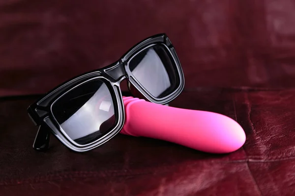 Pink vibrator in sunglass on a red leather background. Mr Cooldick. — Stock Photo, Image