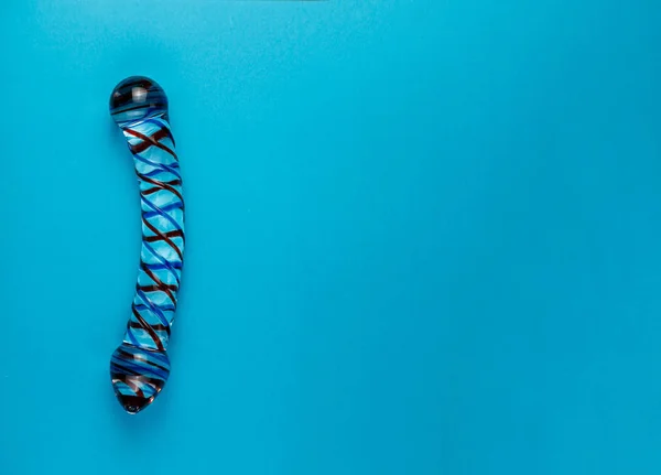 Kopya alanı ile düz mavi arka planda güzel eşit aydınlatmalı cam dildo.