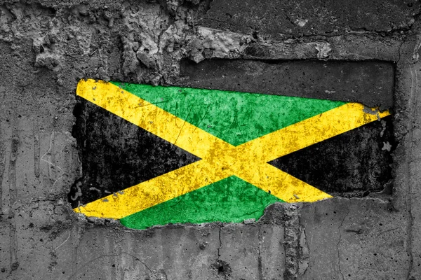 Flaga Jamajki na brudnej drewnianej powierzchni, zbudowany w betonowej bazie, z zadrapaniami i zarysowaniami. Koncepcja utraty lub zniszczenia. — Zdjęcie stockowe