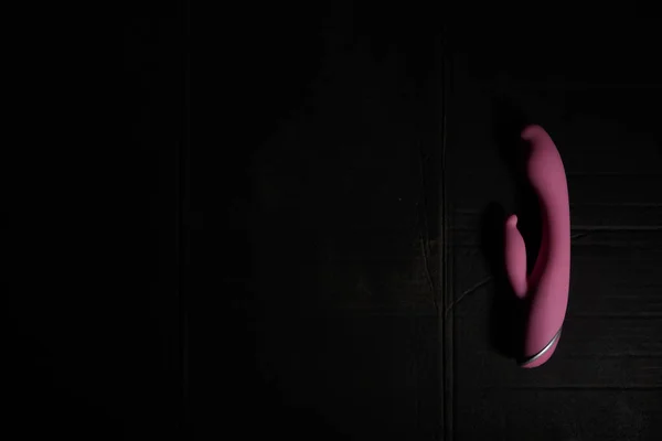 Purple dildo on dirty dark background with hard light and shadows with copyspace. — Stock Photo, Image