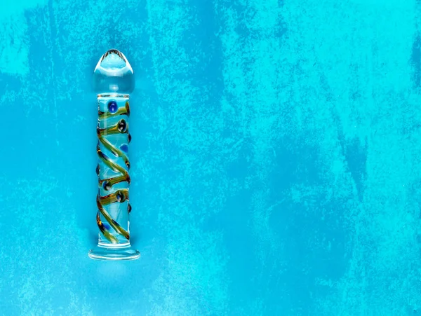 Kopya alanı ile kirli mavi arka planda güzel eşit aydınlatmalı cam dildo.