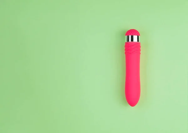 Kopya alanı ile düz yeşil arka planda güzel eşit aydınlatılmış Pembe Dildo.