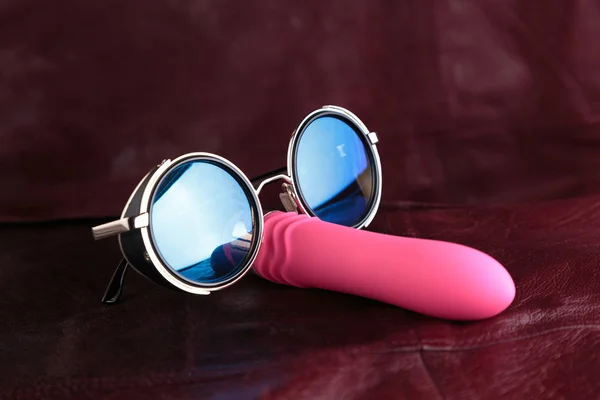 Pink vibrator in sunglass on a red leather background. Mr Cooldick. — Stock Photo, Image