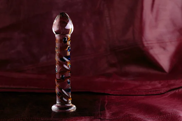 Glass dildo on a red leather background with copy space — Stok fotoğraf