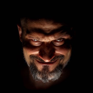 Komedi, muhteşem kötü adam ya da negatif karakter. Sakallı bir adam ile yüz keskin gölgeler ile karanlık bir arka plan karşı yüzün.