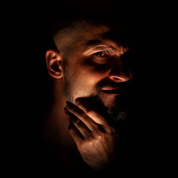 Comique, fabuleux vilain ou personnage négatif. Visage avec un homme barbu grimace sur un fond sombre avec des ombres acérées . — Photo