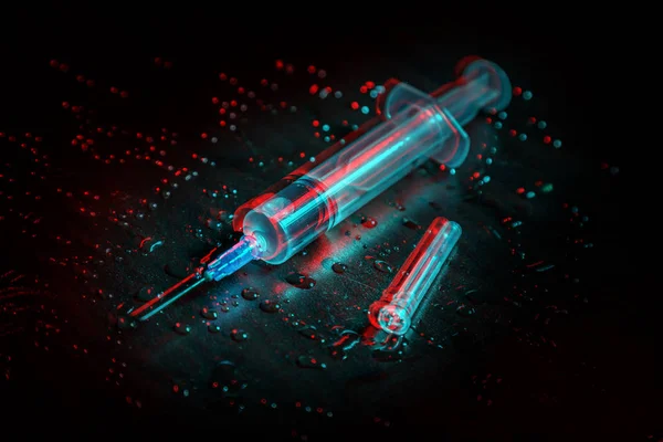 A syringe with a clear liquid lies on a dirty dark background covered with drops. — Stock Photo, Image