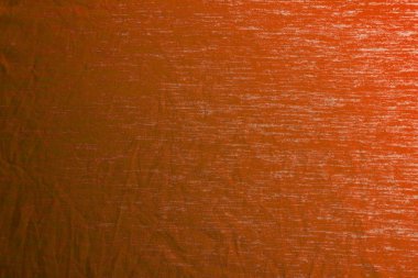 Yumuşak gölgelerle homojen bir şekilde aydınlatılmış turuncu kumaş dokusu.