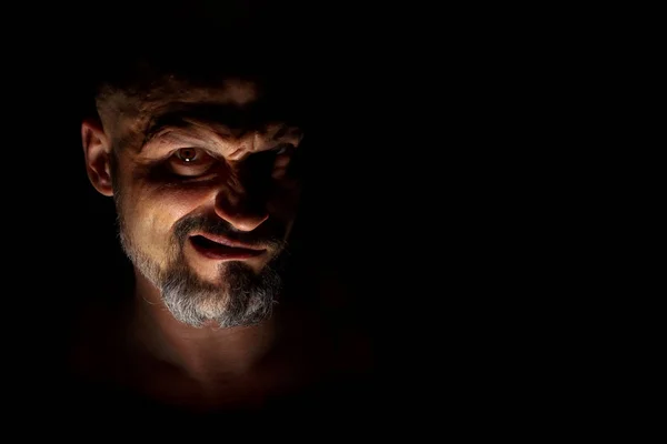 Лицо с бородатым человеком гримаса на темном фоне с острыми тенями. Комедийная, сказочная или отрицательная концепция персонажа с пространством для копирования . — стоковое фото