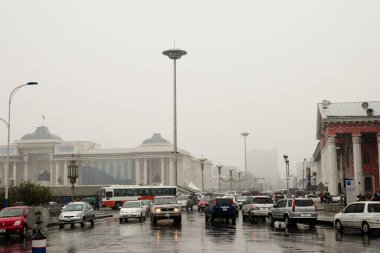 ULAANBAATAR, MONGOLIA - May 11, 2012: Daily traffic on Olympic Street on a snowy day in the capital city clipart