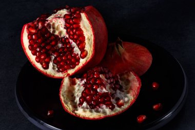 Karanlık bir arka plan üzerine bir tabak üzerinde kırık nar