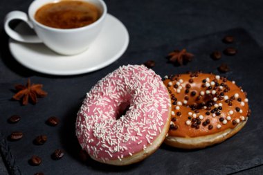 İki donut ve bir fincan kahve koyu gri arka plan üzerinde