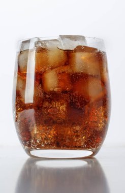 Beyaz bir masada buzlu bir bardak Coca-Cola.
